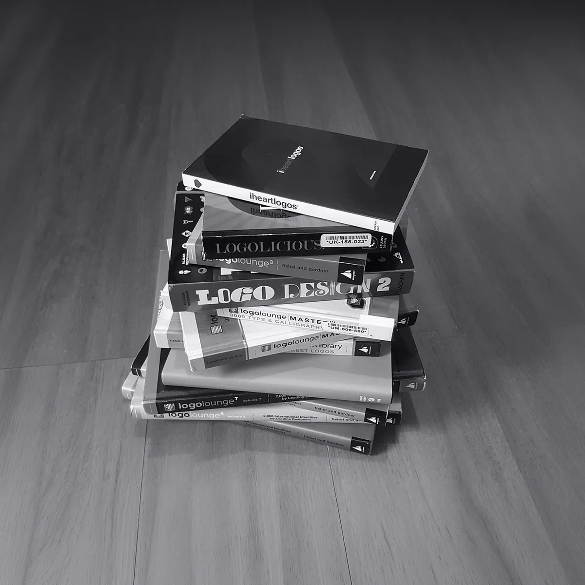 Stack of printed design annuals that feature marks from the studio, including TASCHEN&rsquo;s Logo Design 2 and several LogoLounge volumes